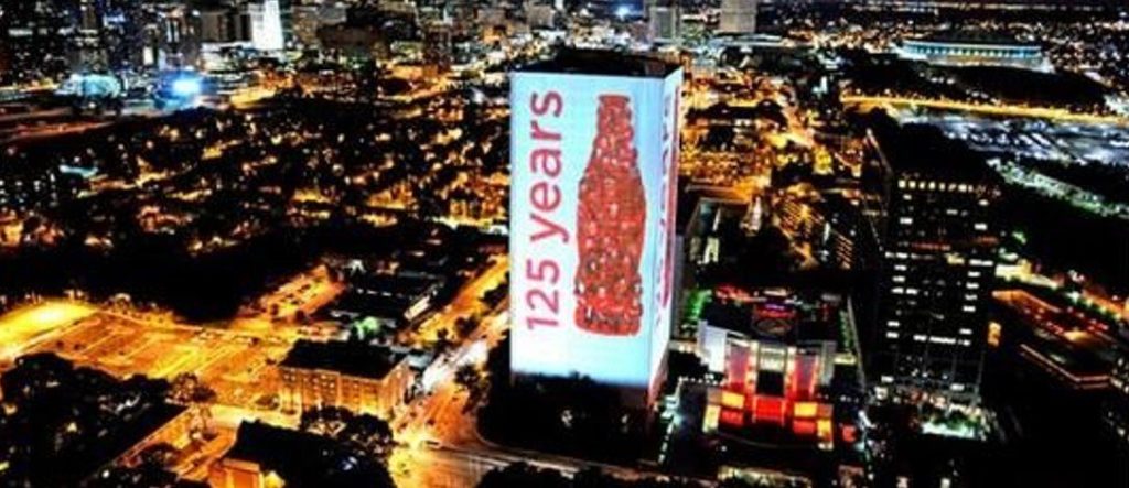 a photo with a huge digital coke billboard surrounding a building. Billboard Lighting Schedules
